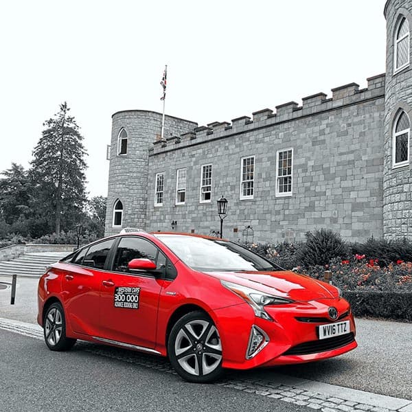 A red Western Cars taxi outside a stone building