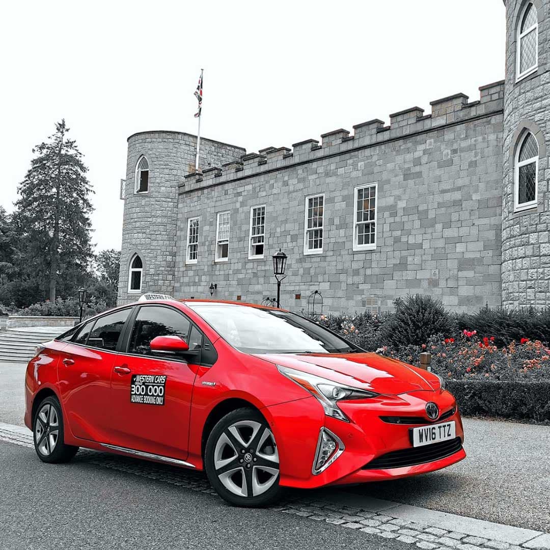 A Western Cars red taxi outside a stone building